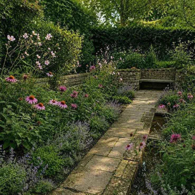 Square garden view of the pollinator border surrounding a stone path